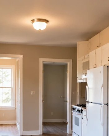 Clean, empty apartment with wood-look floors and white kitchen appliances